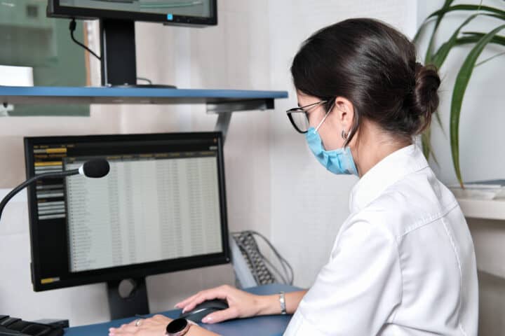 Asian woman doctor searching patient information from medical record system by using computer in hospital